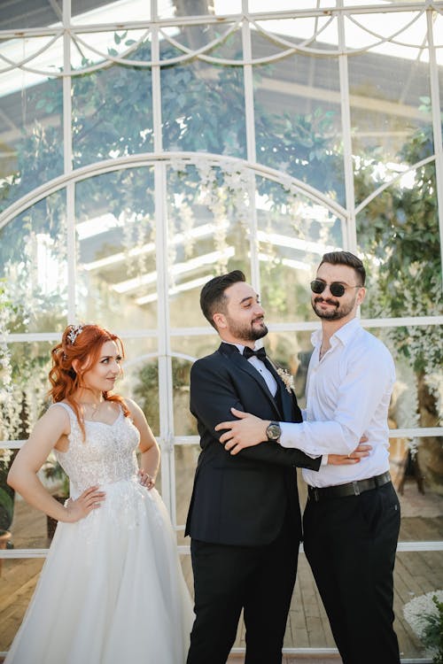 Men Jokingly Holding Each Other Beside a Bride