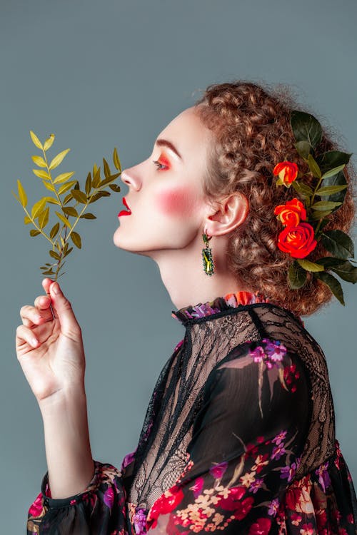 Woman with Flowers on Hair Holding Leaves