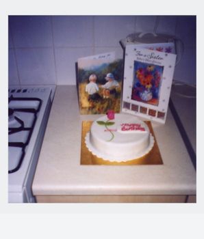 A vintage-style birthday cake with greeting cards on a kitchen counter, invoking nostalgia.