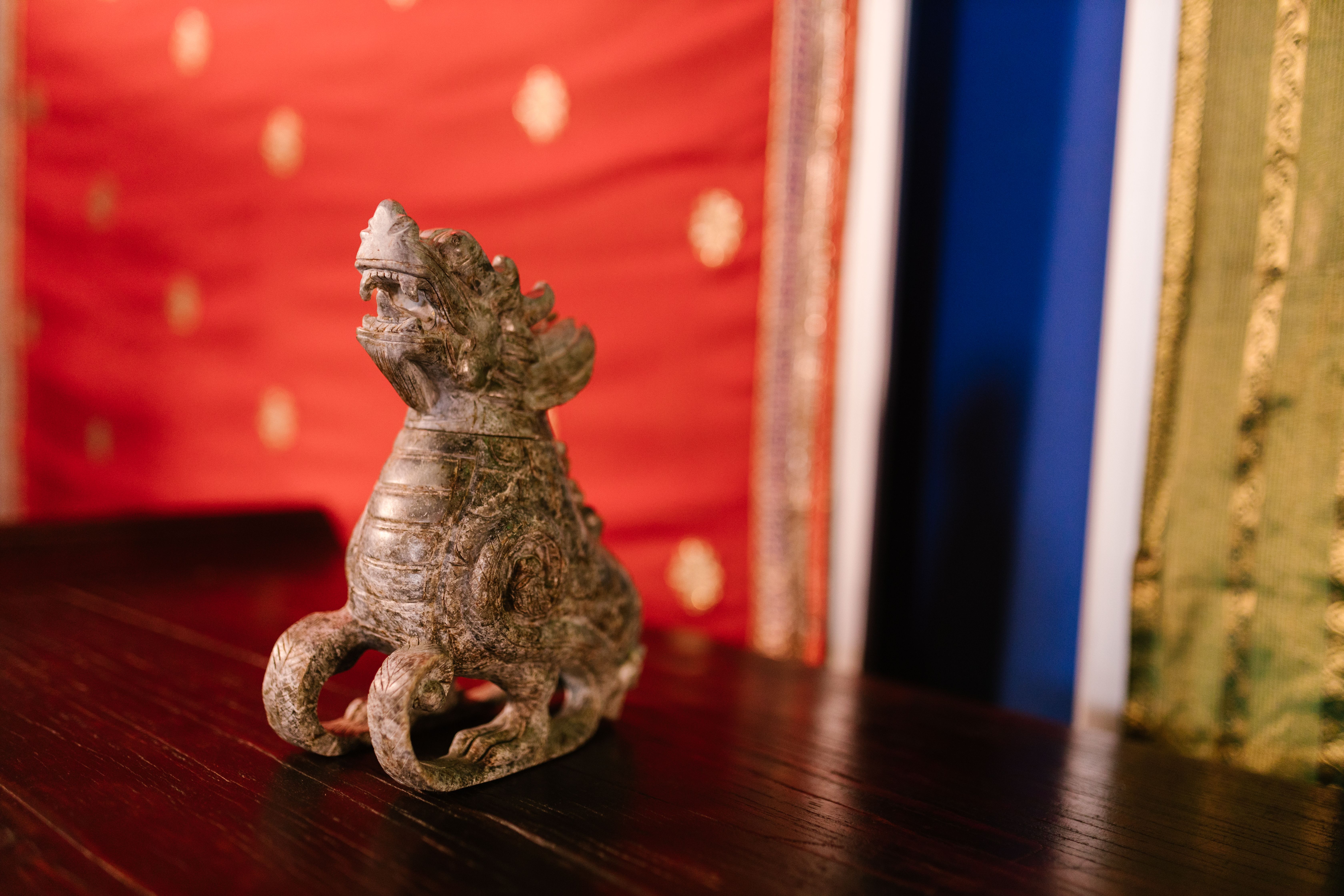 Close-up of an ornate stone dragon figurine on a wooden table with blurred background.