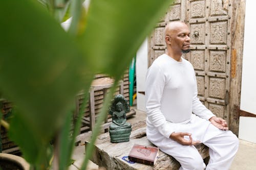 Man in White Long Sleeves and White Pants Meditating