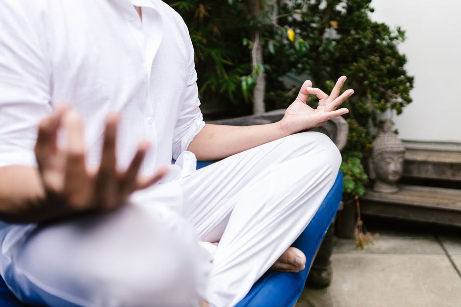 A person in white practicing yoga meditation outdoors in a serene environment.