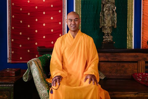 Man in Yellow Robe Sitting on a  Wooden Bench