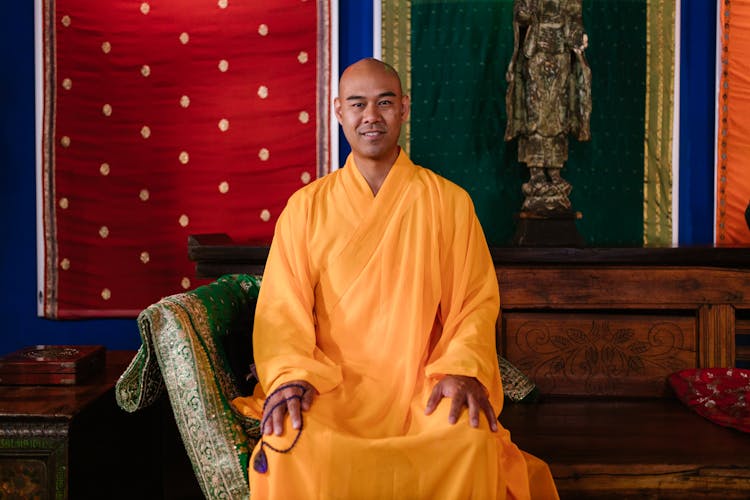 Man In Yellow Robe Sitting On A  Wooden Bench