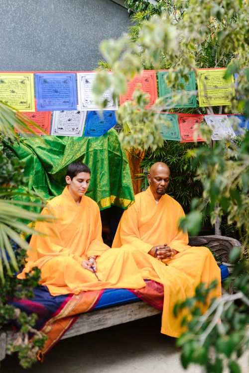 Free Two monks meditate peacefully outdoors in traditional robes, surrounded by colorful prayer flags. Stock Photo