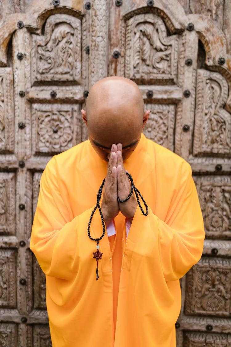 A Buddhist Monk Praying With Prayer Beads