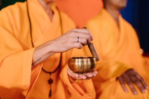 Close-up of Buddhist monks using a Tibetan singing bowl during meditation, promoting peace and mindfulness.