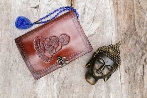 A Buddha Head in Copper Besides a Buddhist Prayer Book