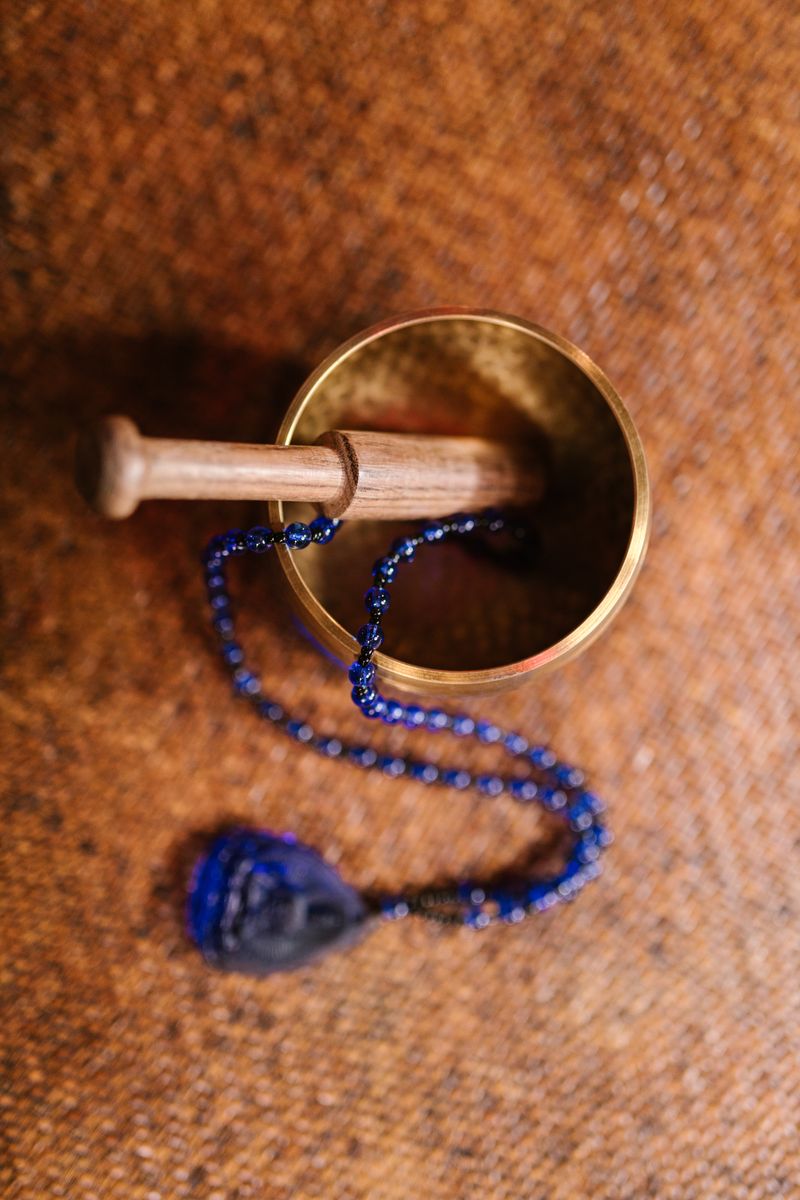 Tibetan singing bowl with mala beads on a woven mat