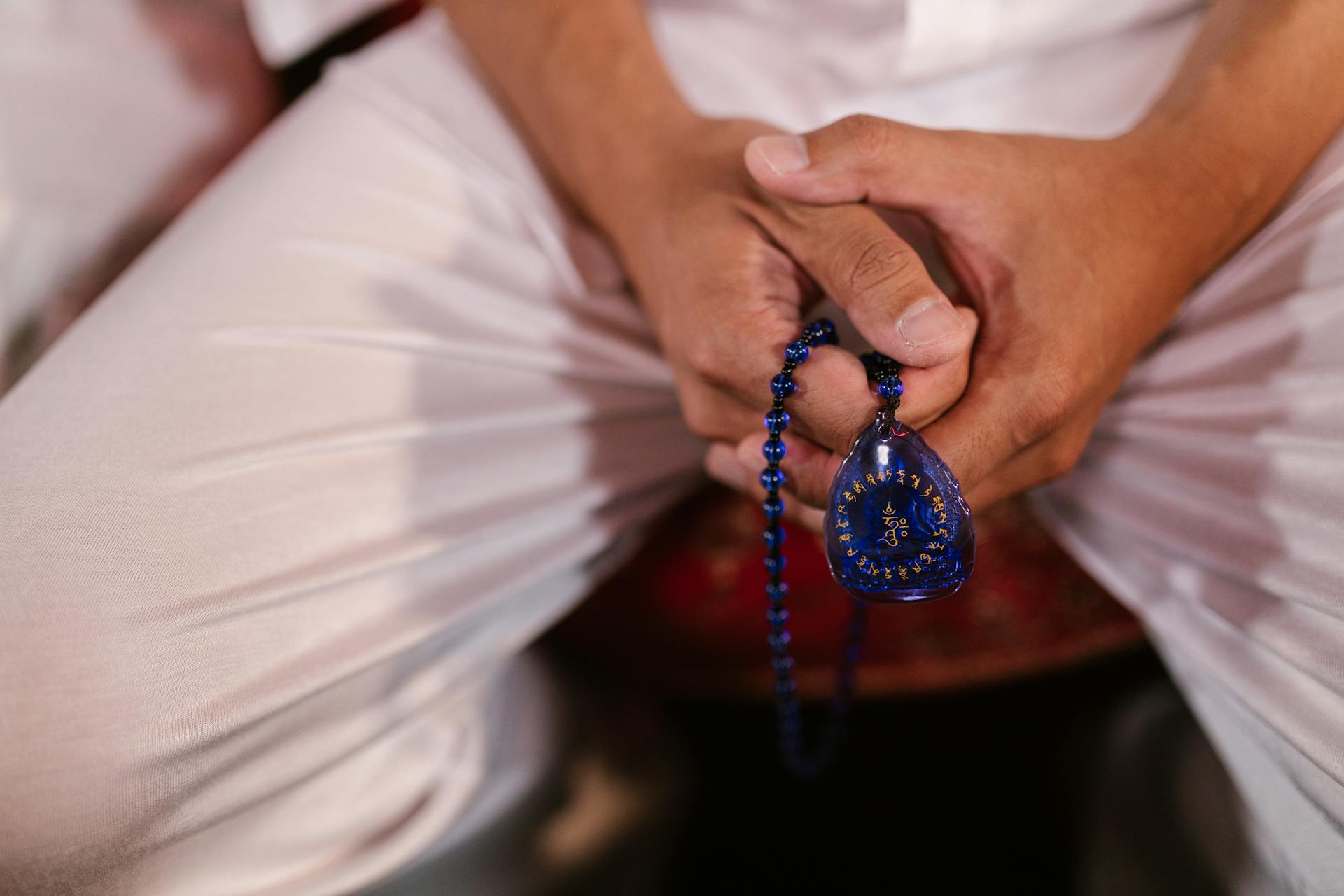 Close-up of hands holding blue prayer beads, symbolizing mindfulness and spirituality.