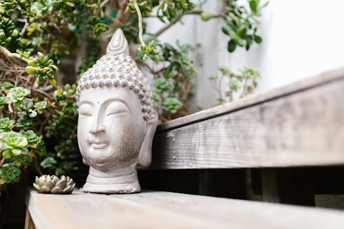 A Buddha Head Bust on a Wooden Counter
