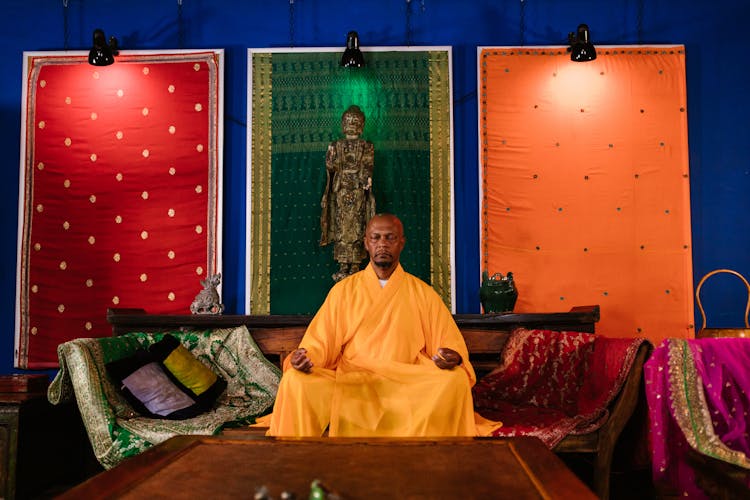 A Buddhist Monk Meditating Over A Wooden Chair