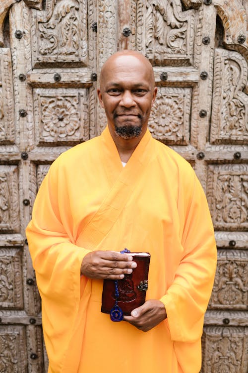 Monk in Yellow Gown Holding Book with Leather Cover