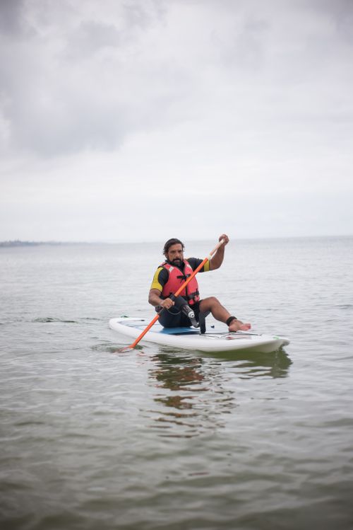 Free Man with prosthetic leg enjoying paddleboarding on calm sea in Portugal. Stock Photo