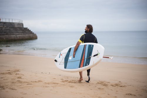 A Man Carrying His Paddleboard