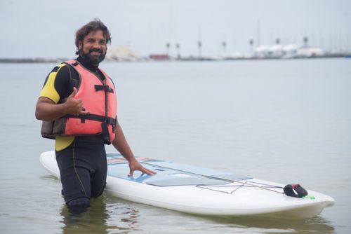 Free Cheerful man with SUP board on a calm beach in Portugal, ready for adventure. Stock Photo