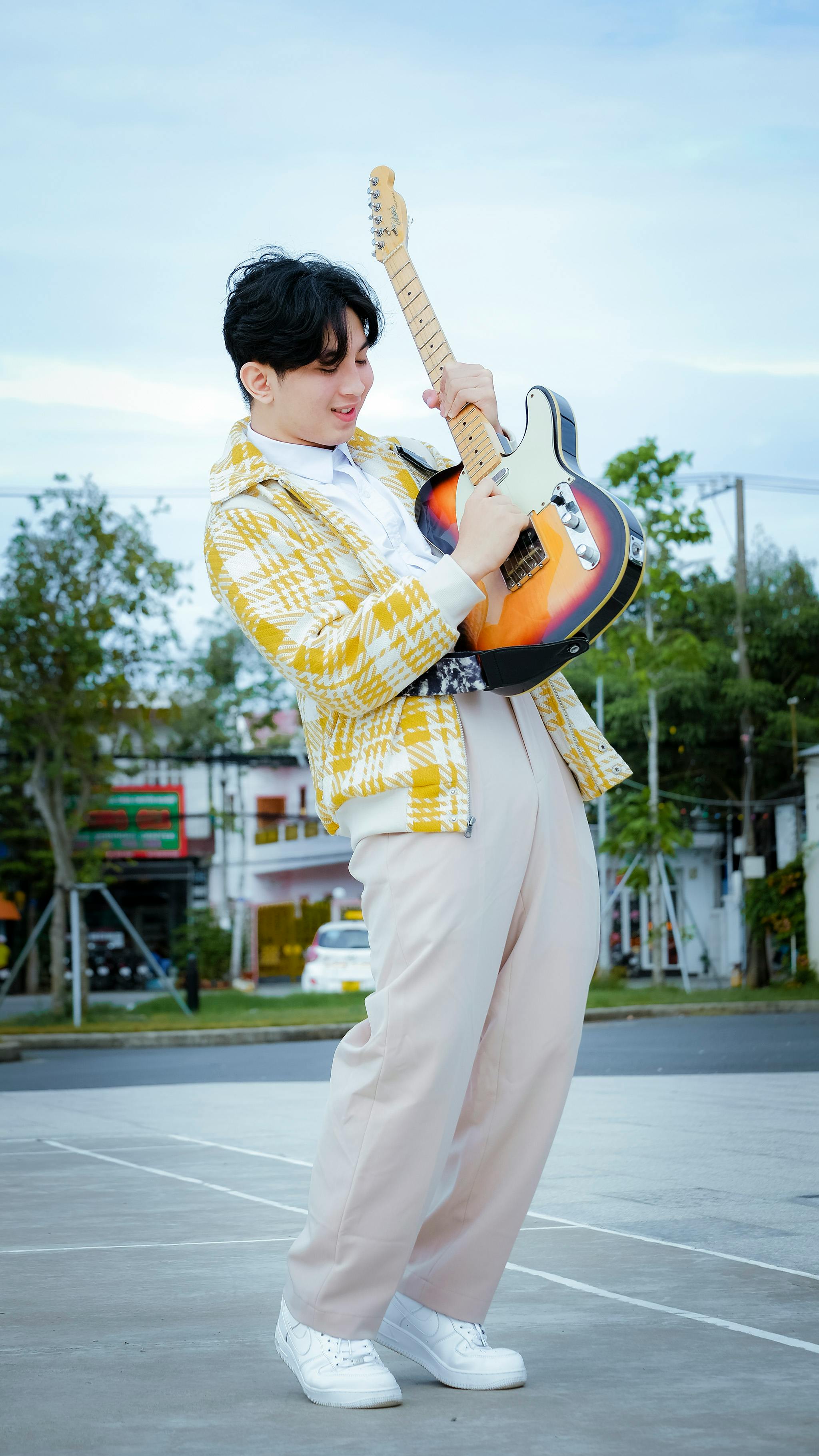 Energetic young musician playing electric guitar outdoors, showcasing vibrant style.