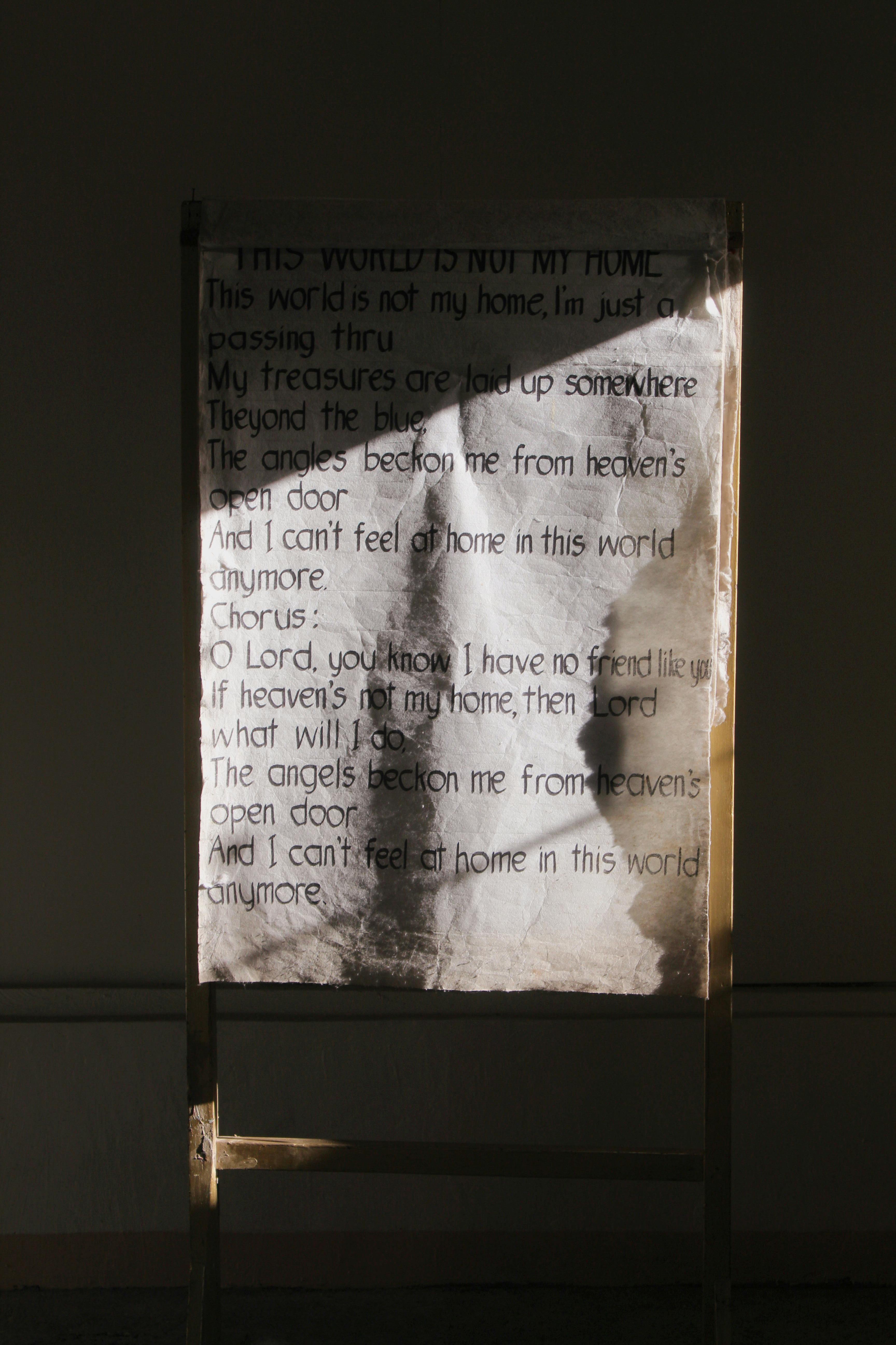Easel displaying a religious hymn, illuminated by sunlight indoors.