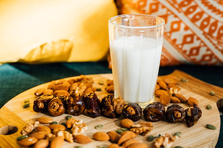 A Glass Of Milk And Mixed Nuts On A Wooden Board