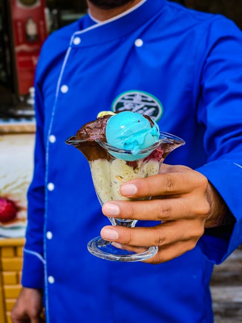 Free A Person in Blue Jacket Holding a Cup of Ice Cream Stock Photo