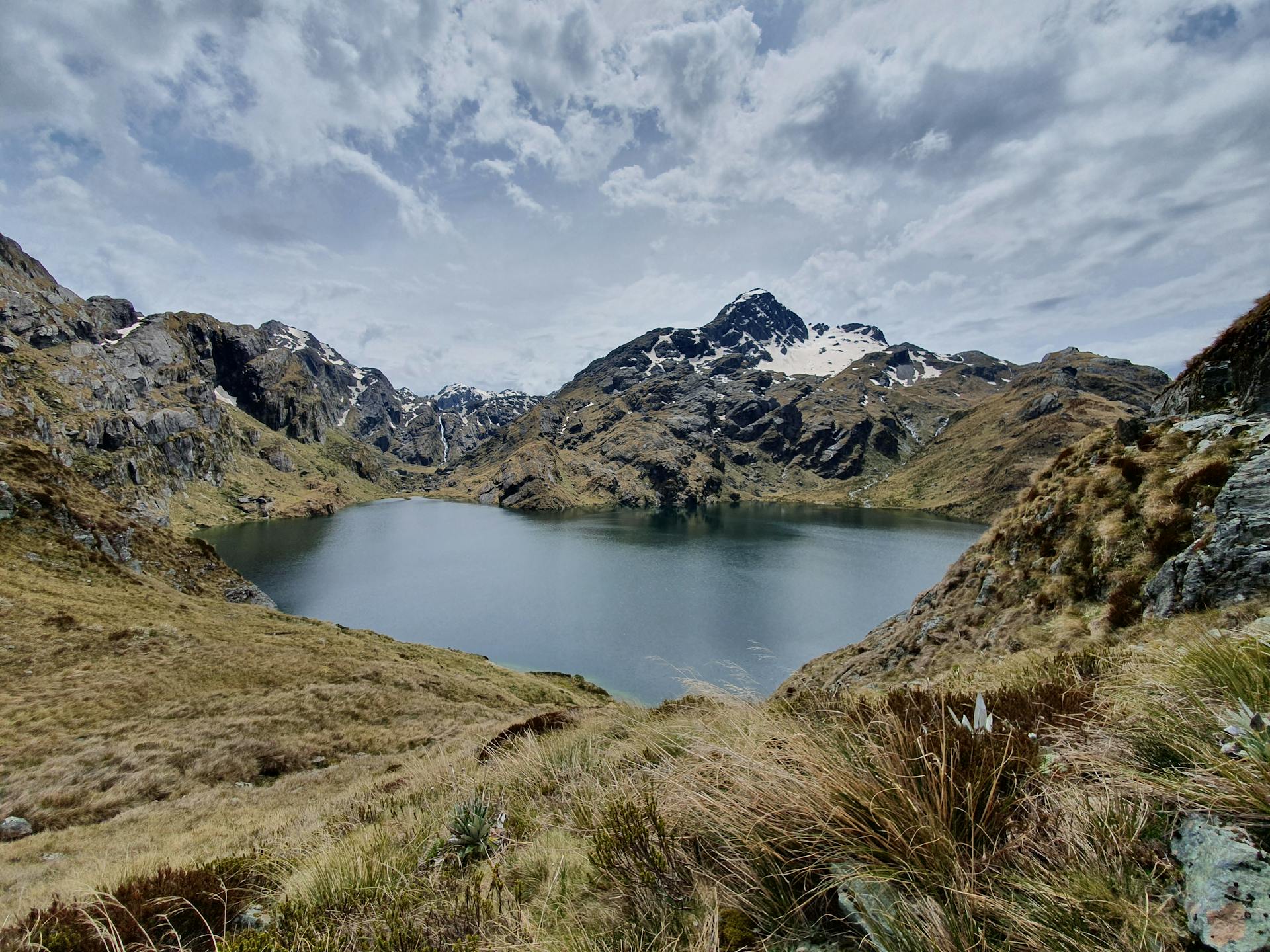 Idyllic mountain lake view with snow-capped peaks in New Zealand's wilderness.