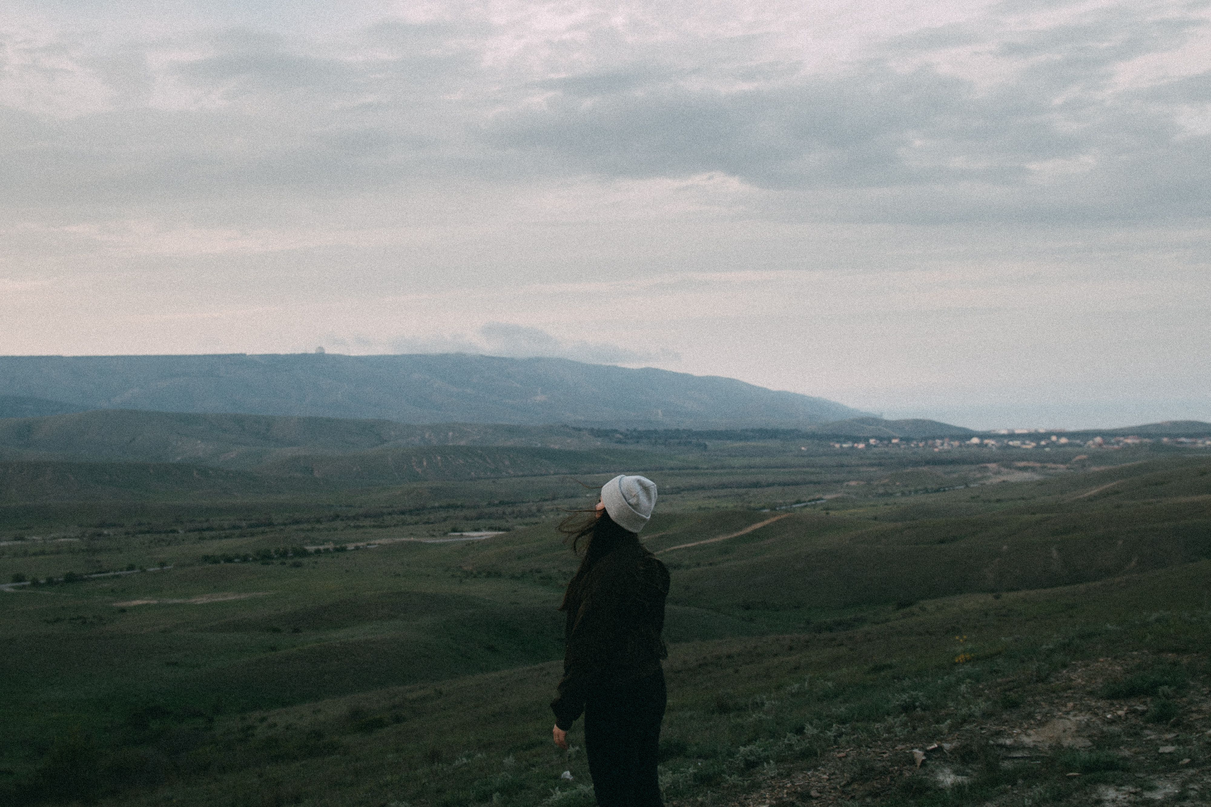 Woman observing the vast landscape of Koktebel under cloudy skies, embracing nature's serenity.
