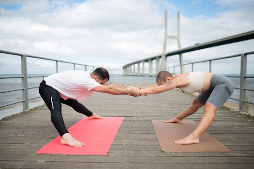 Couple practicing paired yoga poses on a boardwalk next to Vasco da Gama Bridge, Lisbon. Promotes healthy lifestyle.