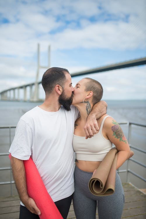 A Couple Holding Rolled Yoga Mats Kissing