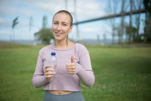 Free A woman happily gives a thumbs up while enjoying leisure with a water bottle outdoors in Portugal. Stock Photo