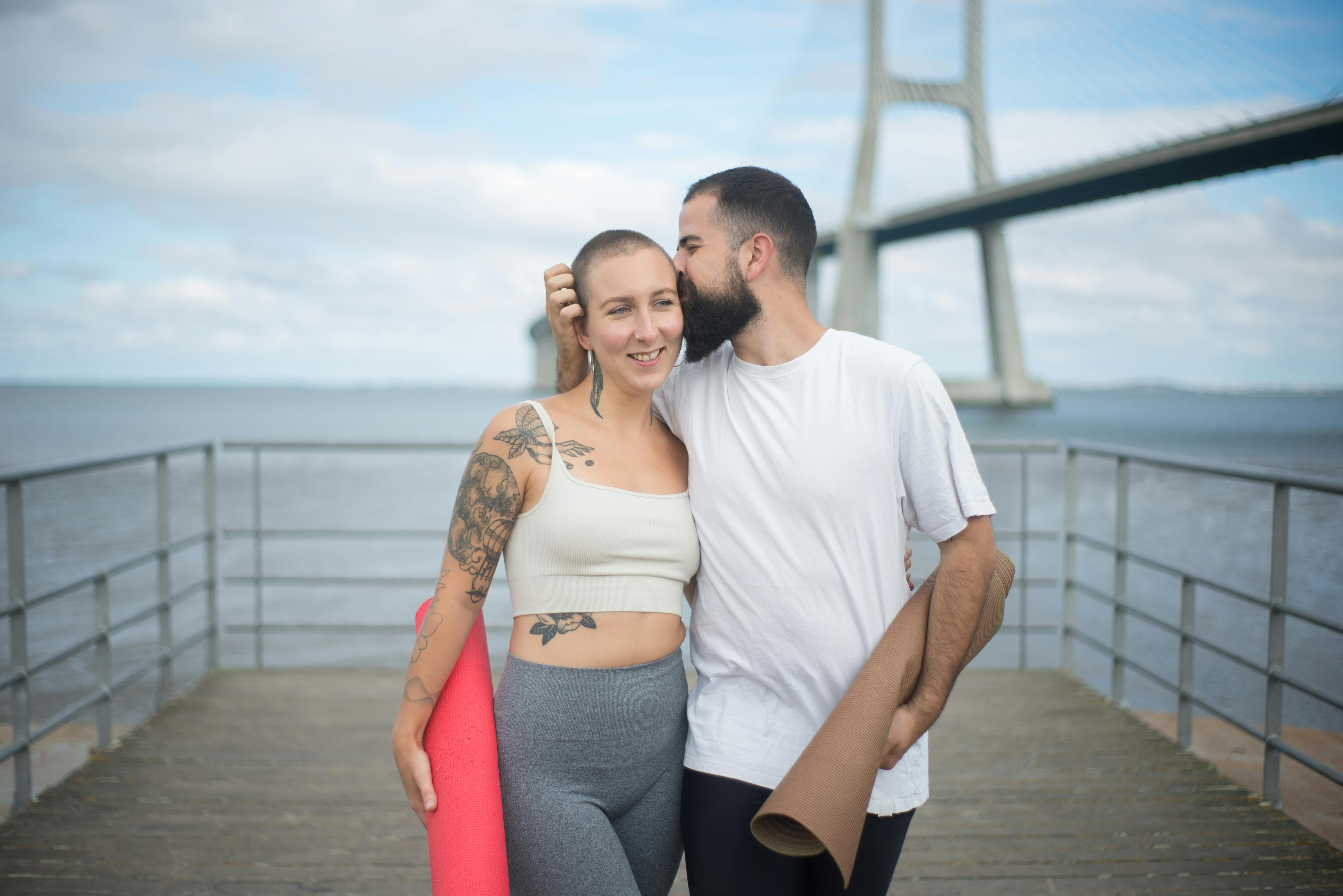 a bearded man kissing a tattooed woman