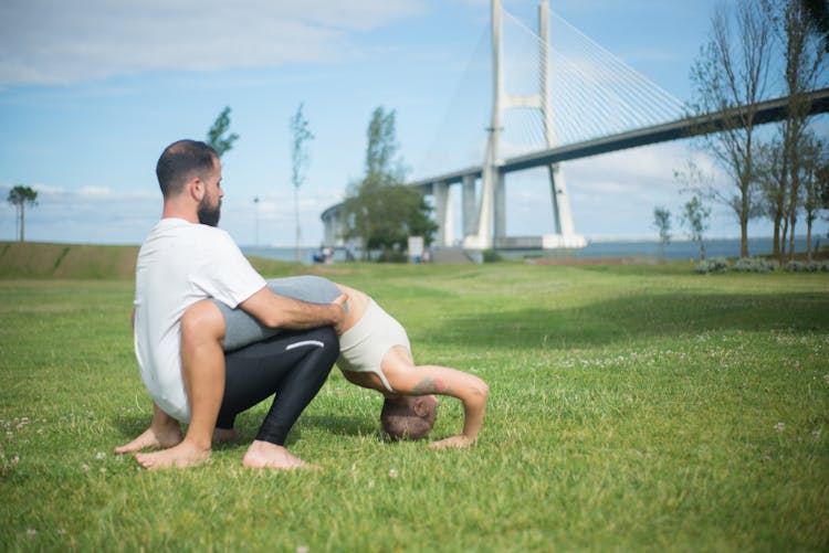 A Couple In Activewear Doing A Couples Yoga In The Park 