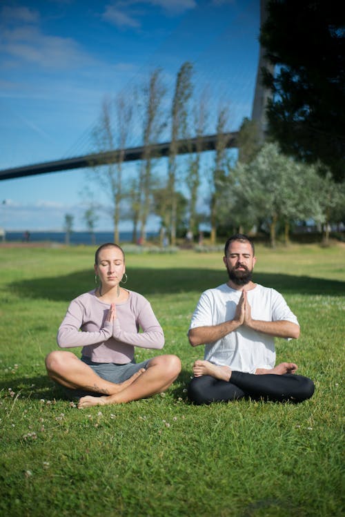 Man and Woman in Meditation Position on Green Grass