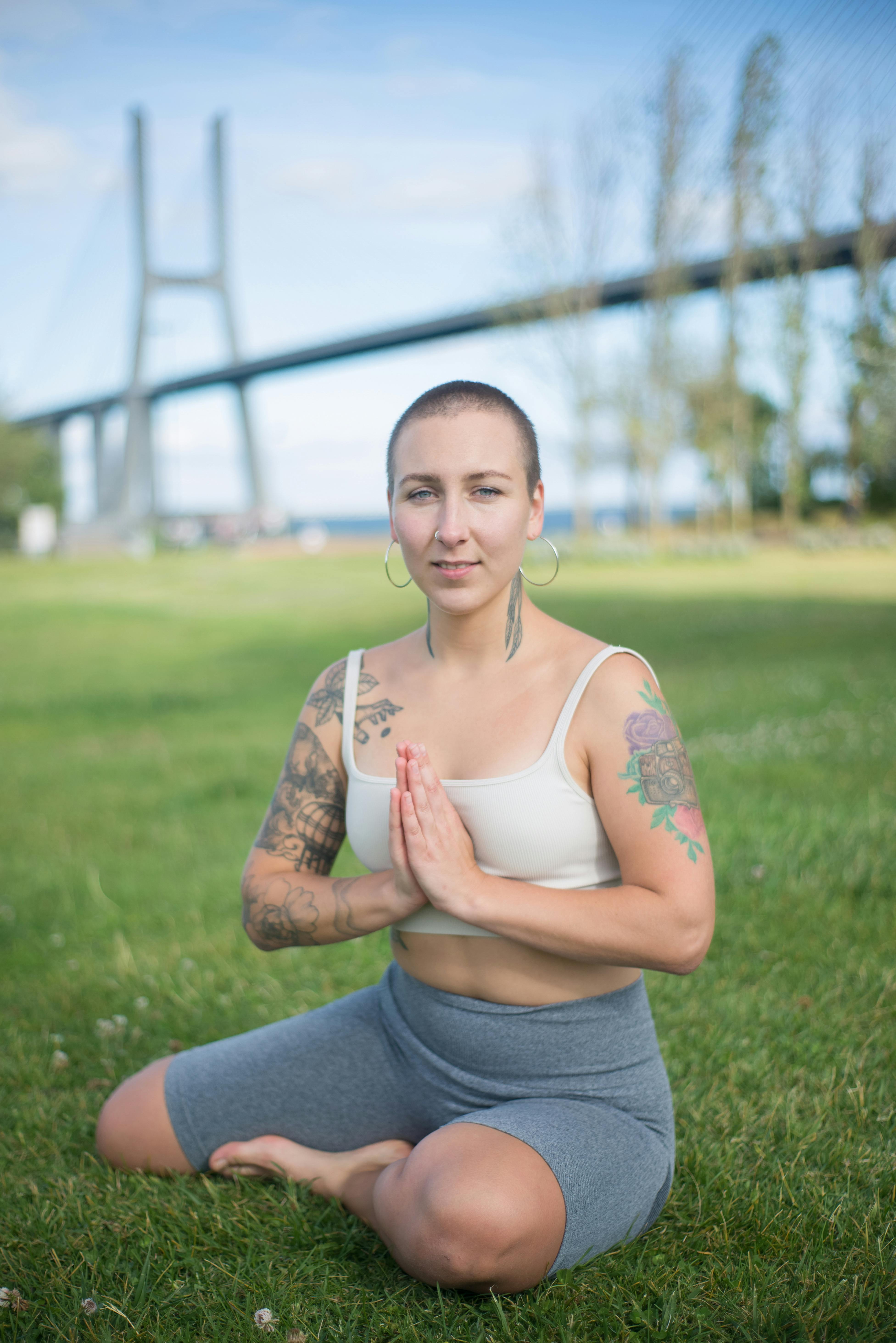 a woman meditating on the grass field