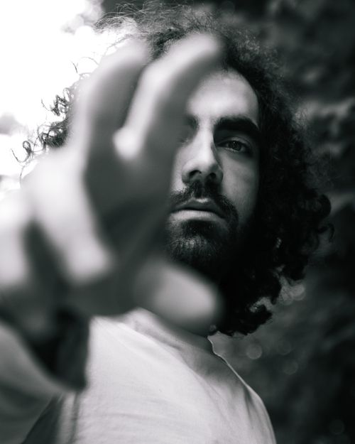Free Moody black and white portrait of a man reaching towards the camera with focus on expression. Stock Photo