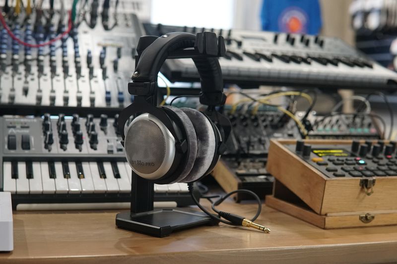 Close-up of headphones and synthesizers in a modern music studio setup.