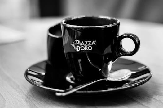 Black ceramic cup with espresso, elegantly displayed with a saucer and spoon.