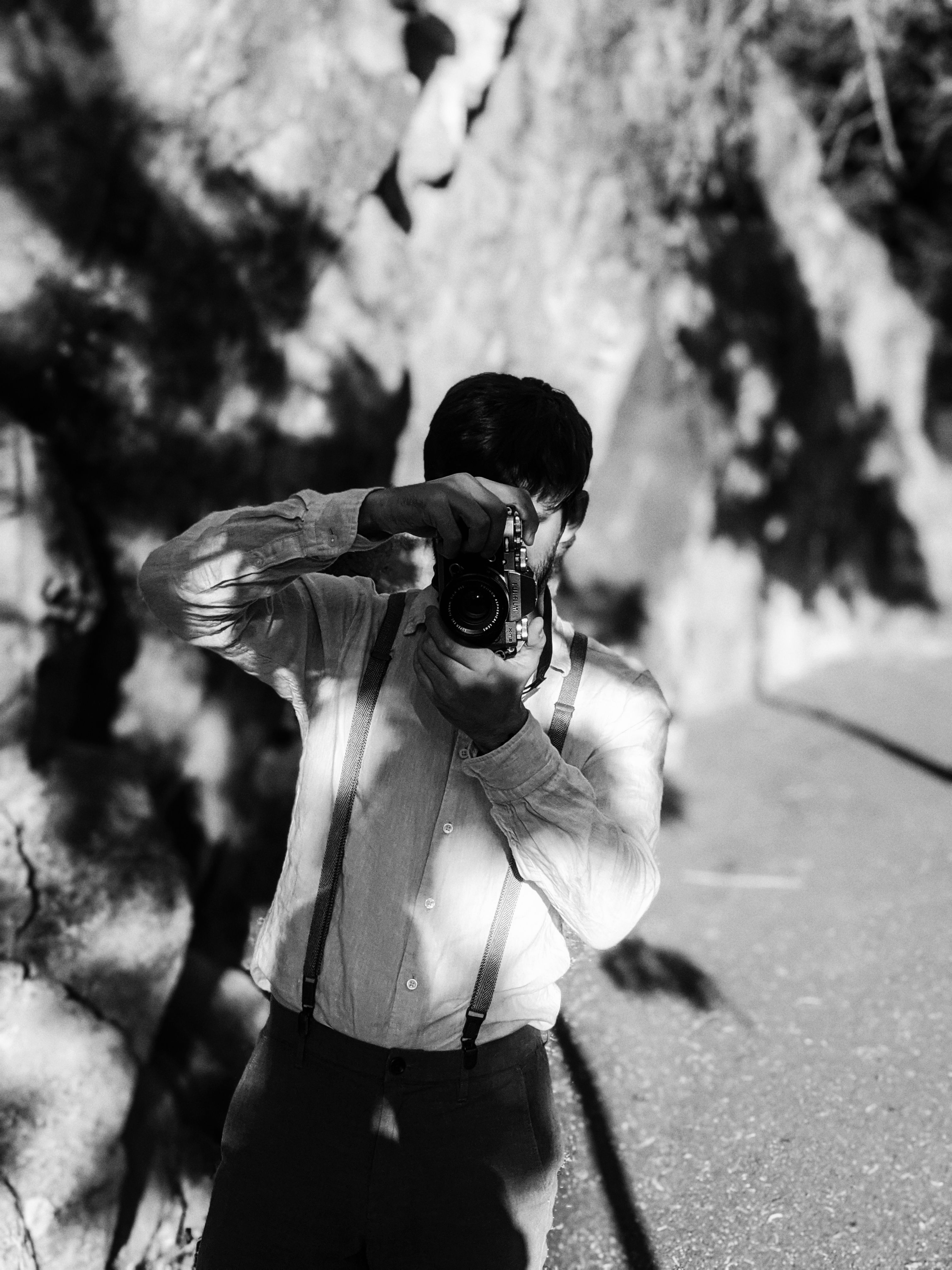 Stylish monochrome photo of a photographer in vintage attire capturing an outdoor scene.