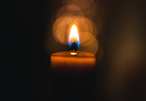 A Lighted Candle with Round Light Reflections in Dark Room