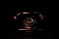Vintage black rotary phone in a dark setting highlighting its classic design and retro appeal.