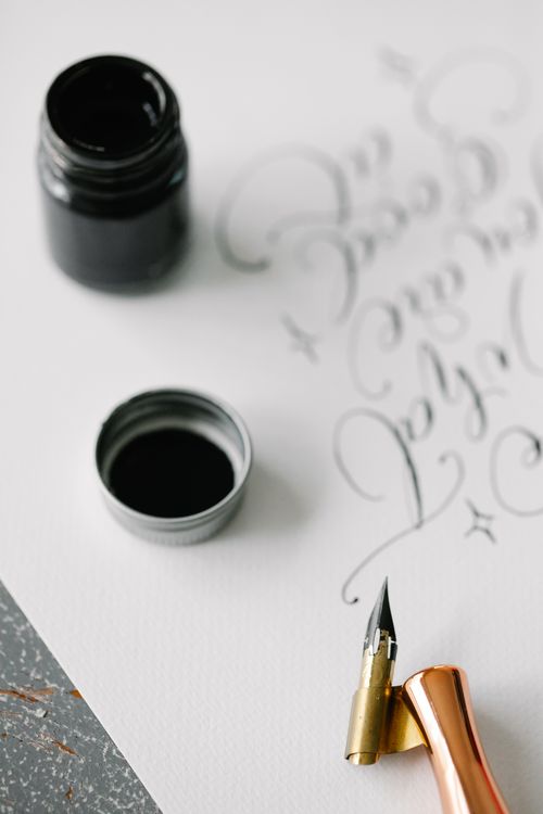 Free Close-up of calligraphy script with black ink and an elegant dip pen on textured paper. Stock Photo