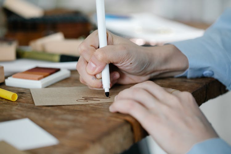 A Person Writing On A Piece Of Cardboard