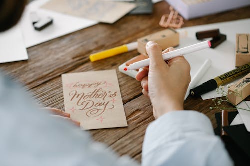 A Person Holding a Pen Writing on a Greeting Card