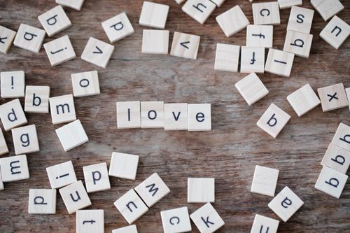 Free Scrabble tiles spelling 'love' on a rustic wooden surface, offering a charming and playful aesthetic. Stock Photo