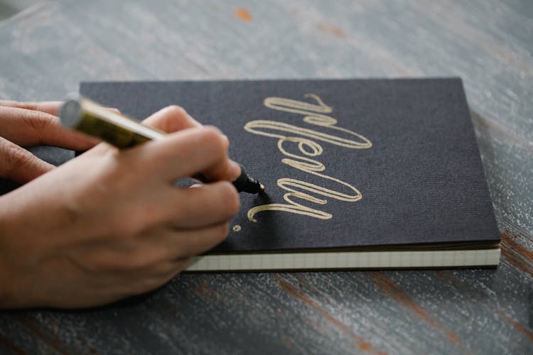 Person Writing On The Cover Of A Notebook Calligraphic Letters 