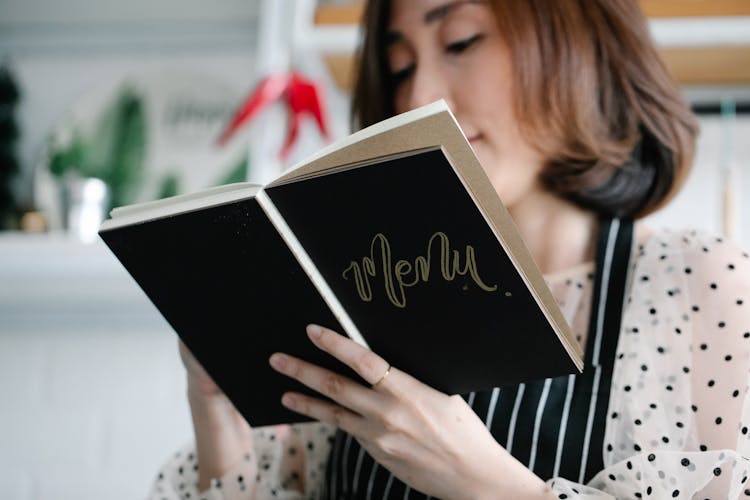 A Woman Holding A Black Menu Book