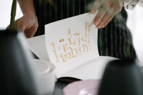 Hands turning a page of handwritten kitchen notes — photo by Katya Wolf on Pexels