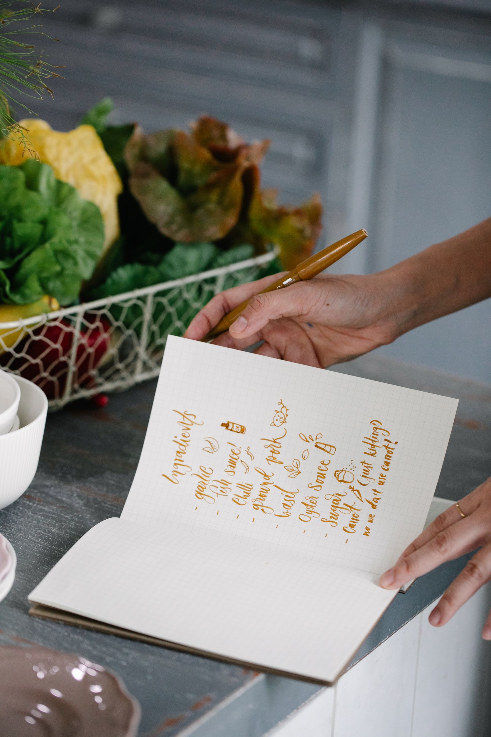 Notebook and pen on a kitchen table with vegetables