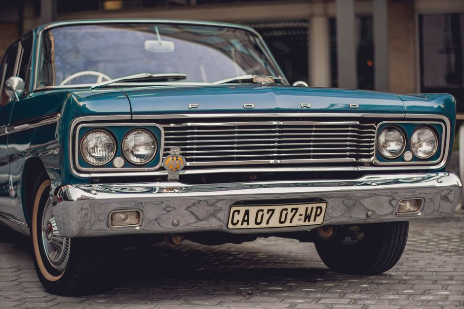 Close-up of a parked classic vintage Ford with a prominent grille and emblem.