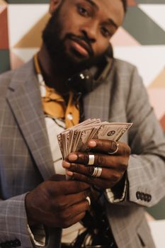 A stylish man in a suit talks on a vintage phone while holding dollar bills.
