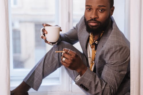 A Man Holding a Cup of Hot Drink and a Cigarette